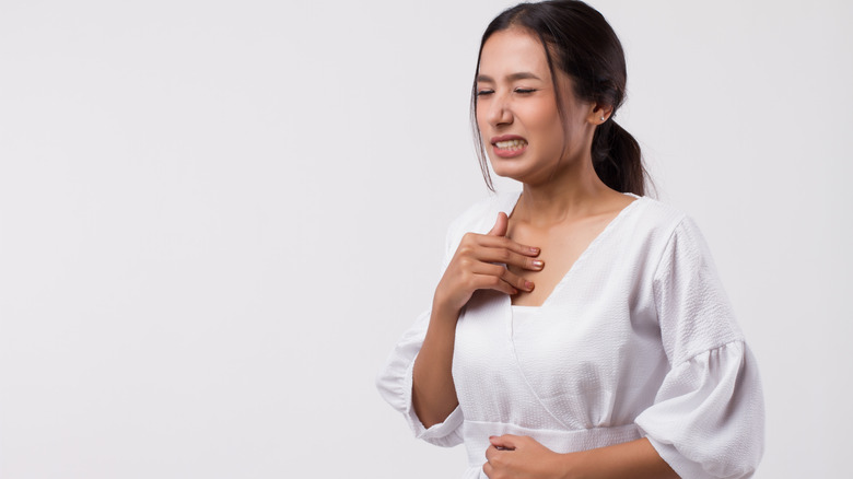 woman holding her neck and stomach feeling heartburn pain