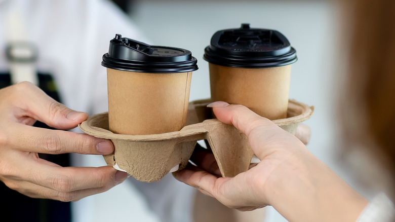 barista serving two cups of to-go coffees 