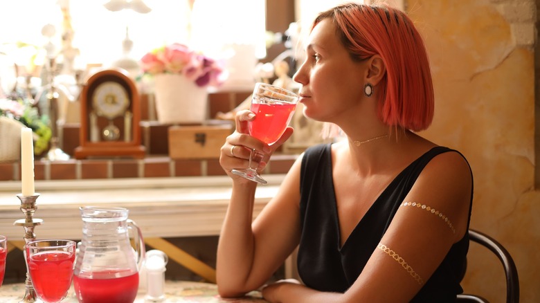 A woman drinking cranberry juice while sitting at a restaurant