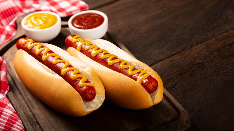 hot dogs with ketchup and mustard on wooden board