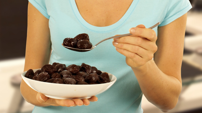 Woman eating prunes for constipation relief