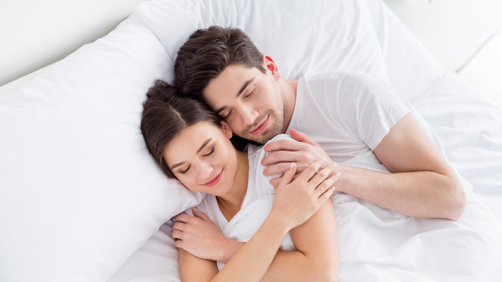 Couple in white bed cuddling