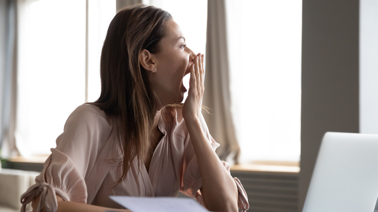 Woman yawning with hand over mouth