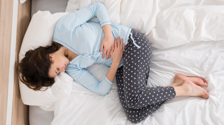 Woman with stomach pain and constipation, lying in bed