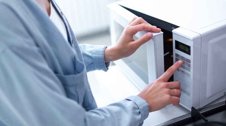 person setting timer on microwave