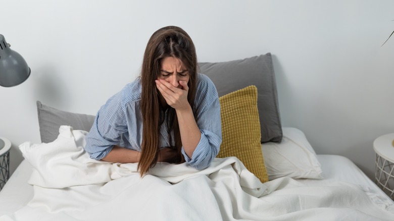 woman sitting in bed covering hand and mouth