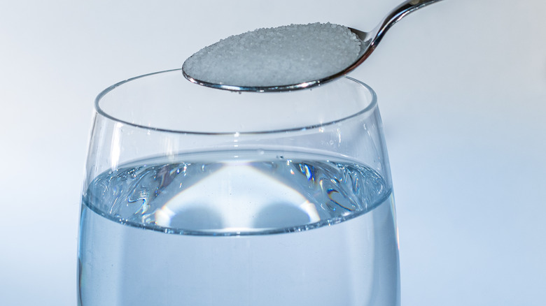 Spoonful of salt over water glass