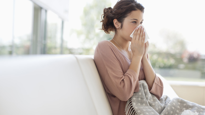 Woman blowing nose with flu