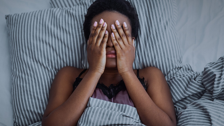 african american woman with insomnia lying in bed 