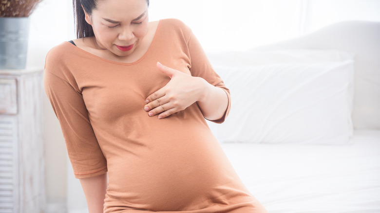 Wincing pregnant woman with heartburn 