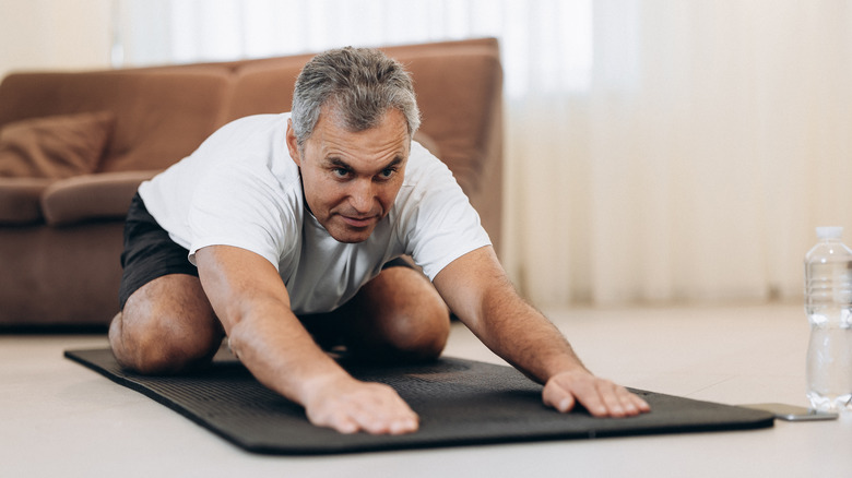 Older man stretching on exercise mat