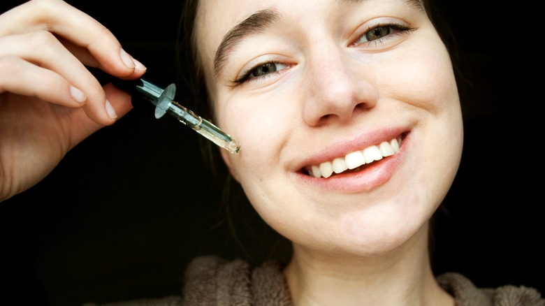 Woman holding tea tree oil dropper