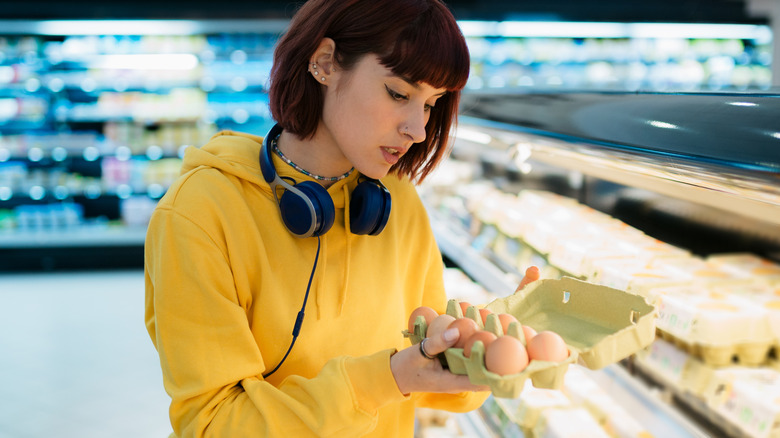 young woman buying eggs at grocery
