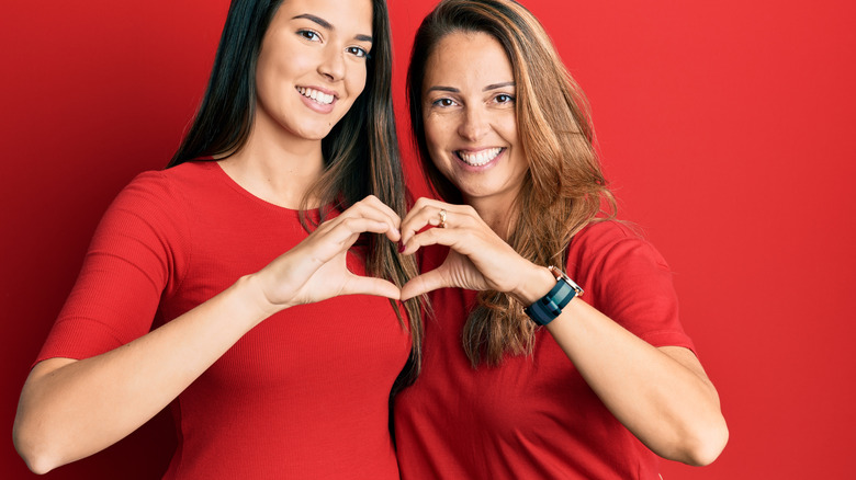 women wearing red and forming heart
