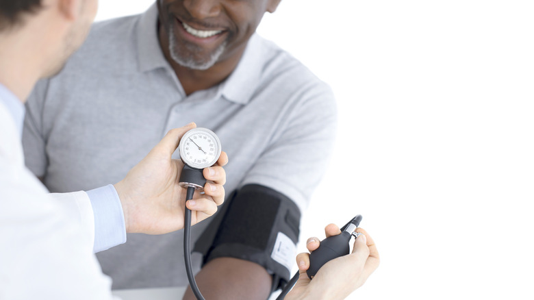 smiling man getting blood pressure examined