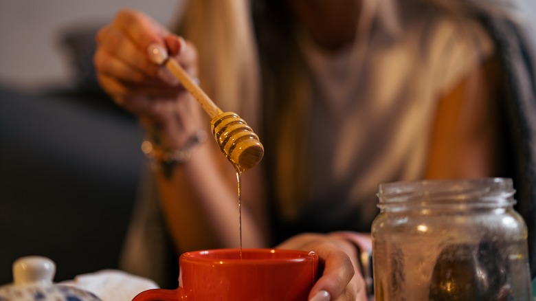 Woman adding honey to mug