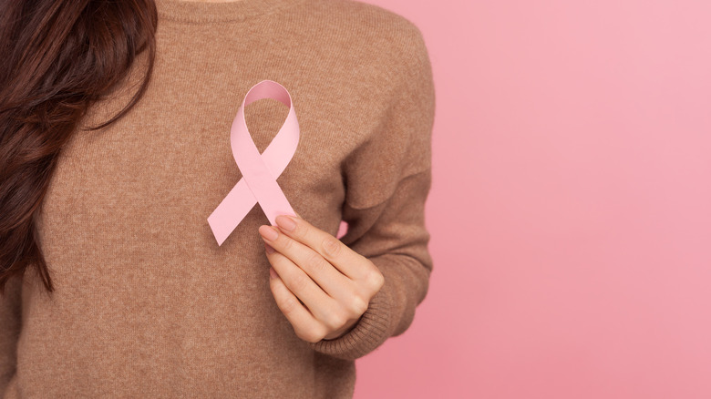 A woman holds a pink breast cancer ribbon