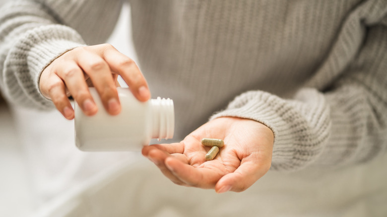 woman shaking pills into hand