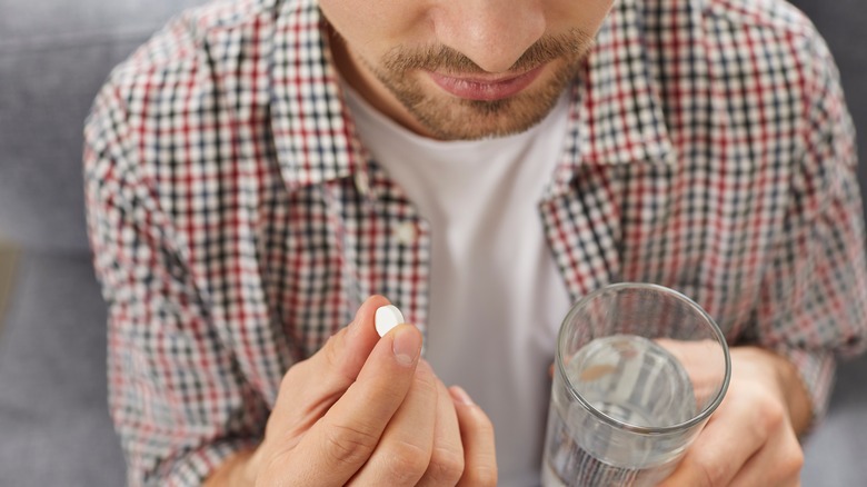 man taking pill with water
