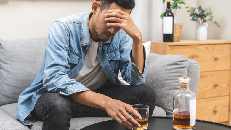 A man with his face in his hand and struggling with alcohol misuse