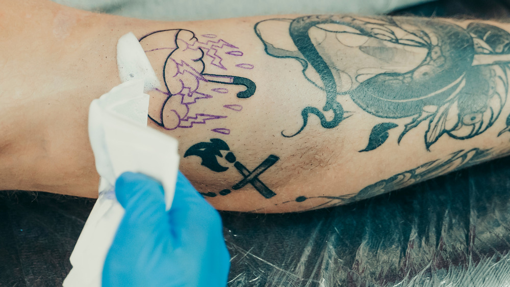tattoo artist cleaning the newly tattooed skin 