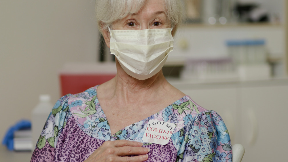 Woman showing her COVID-19 vaccination sticker