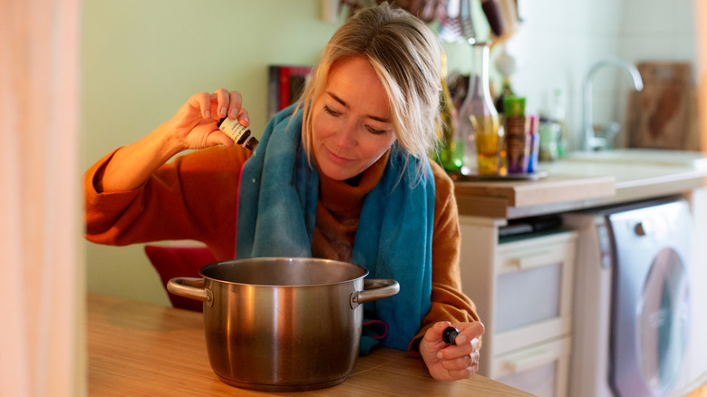 woman putting essential oil into pot of boiled water