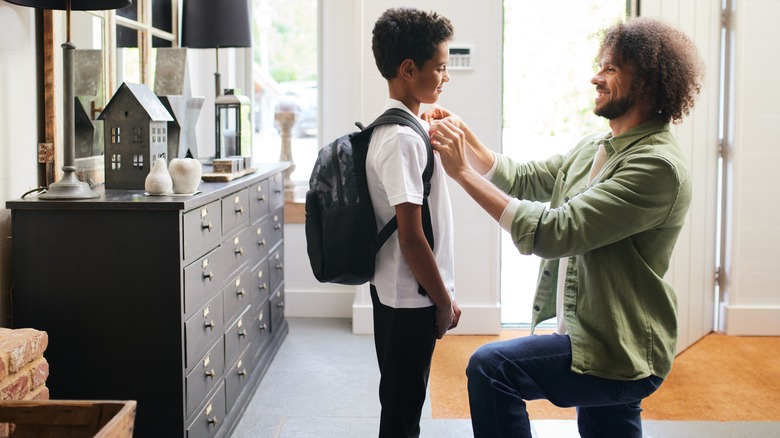 father helps son get ready for school