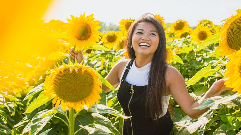 Young woman laughing in field of sunflowers
