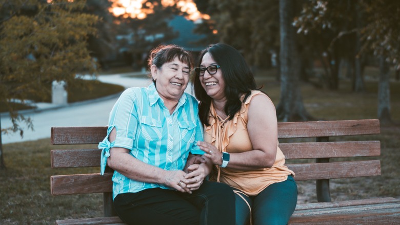 Two women laughing together on a bench