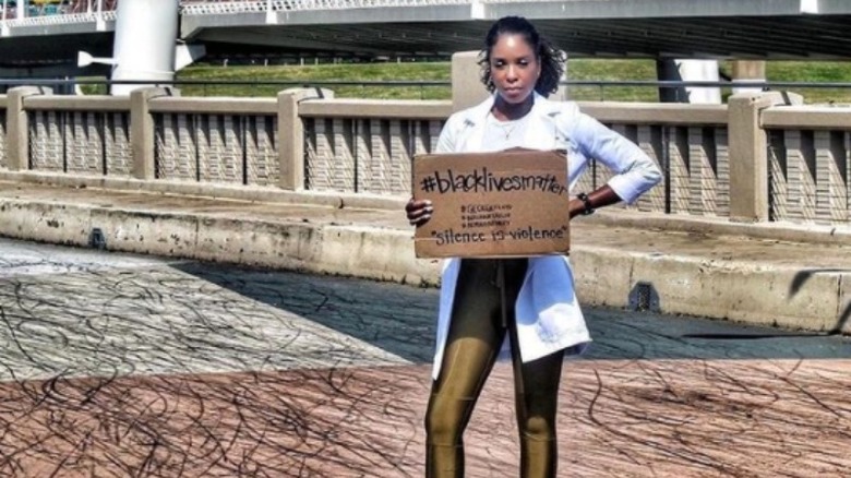 Dr. Shepard outside in a lab coat holding a Black Lives Matter sign