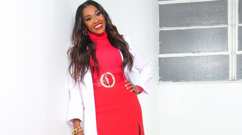 Dr. Nita Landry smiling in white coat and red sweater