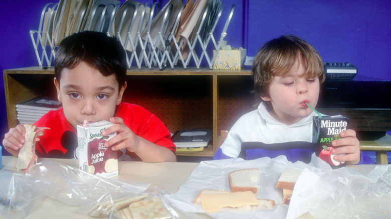 Children drinking apple juice boxes 