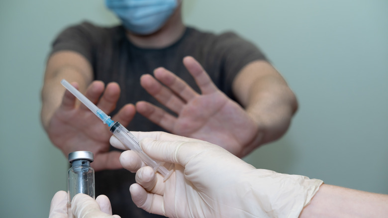 Man holding his hands up to refuse a vaccine