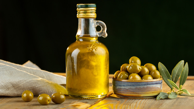 Bottle of olive oil next to a bowl of olives