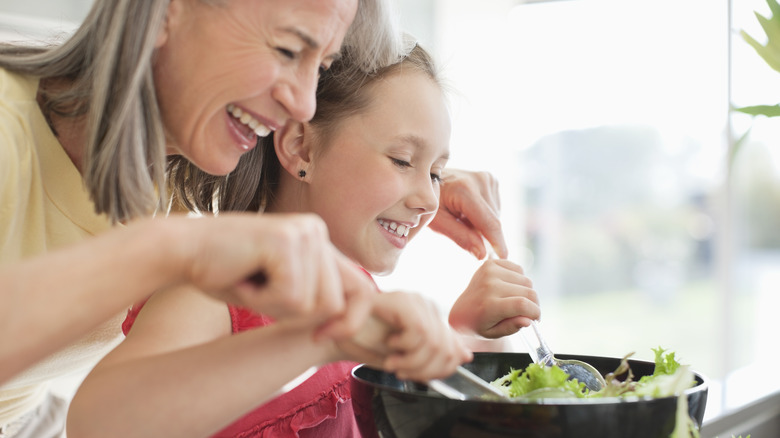 woman and young girl mixing a salad