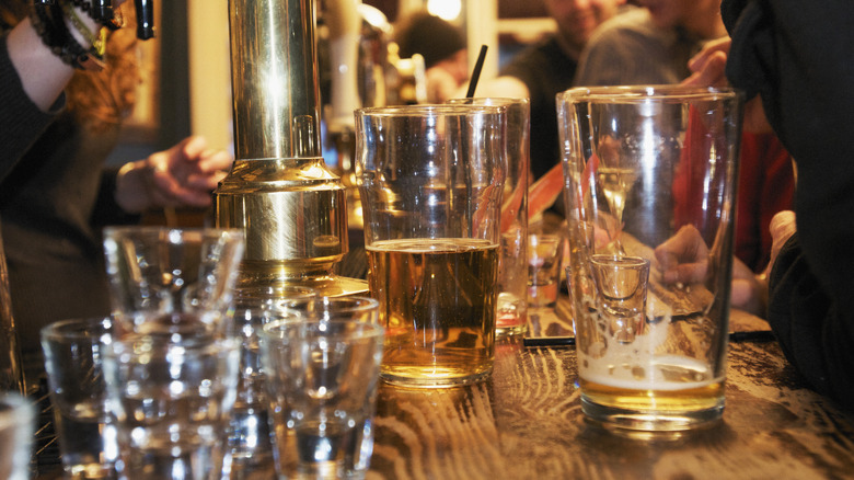 Several types of empty and half-empty bar glasses on a bar