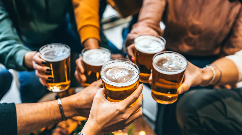 multiple people holding beer glasses