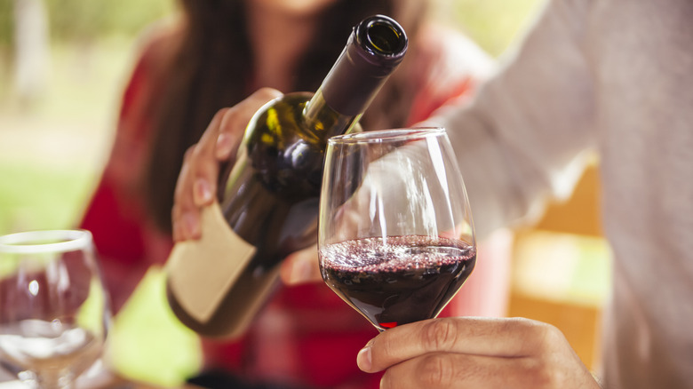 A man's hand pouring a glass of red wine