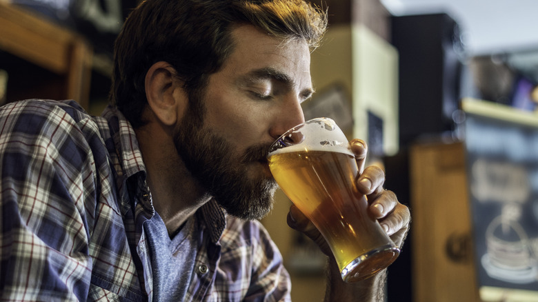 A man closing his eyes while drinking a beer