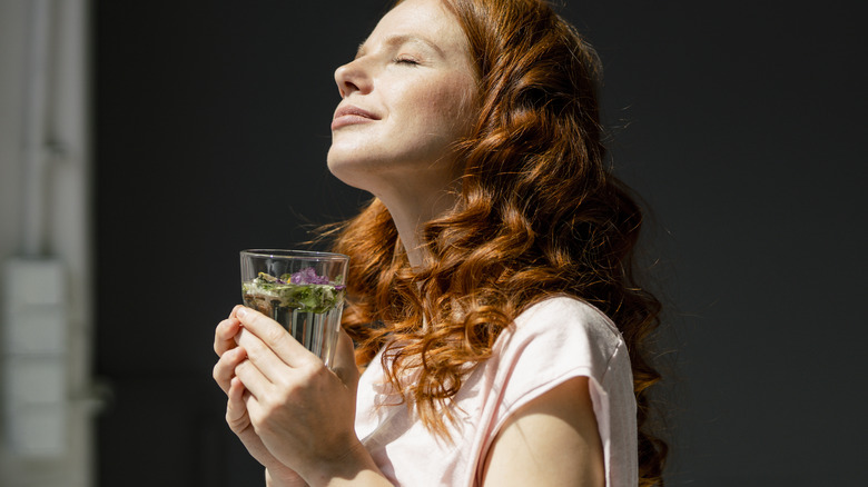 woman holding a glass of water while looking out the window