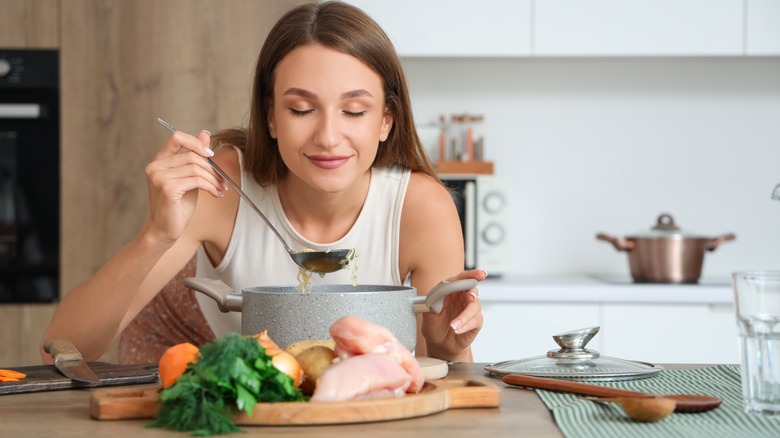 woman smelling a ladle of chicken soup