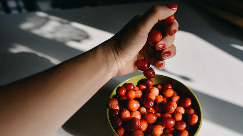 woman dropping cranberries in bowl