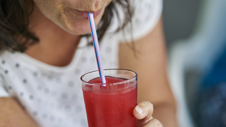 woman sipping red drink with a straw