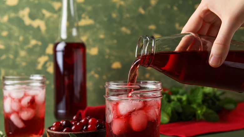 woman's hand pouring cranberry juice into glass