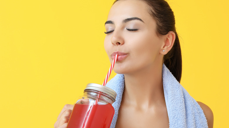 woman drinking red juice from a mason jar glass