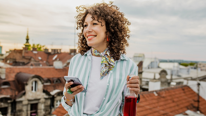 smiling woman sitting on rooftop with red drink