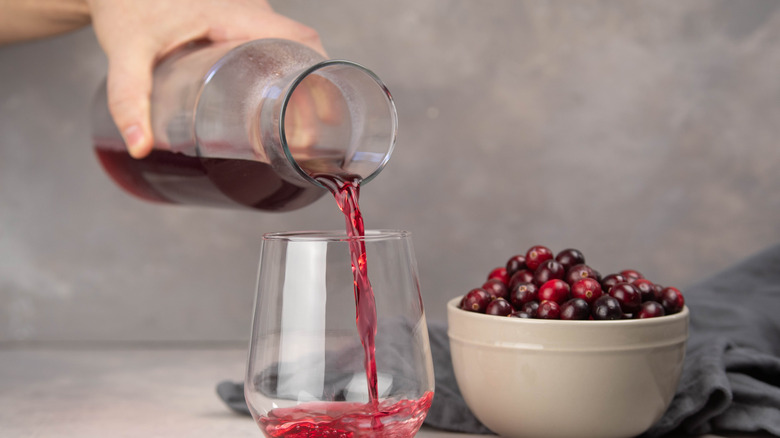 woman pouring cranberry juice with fruit in bowl