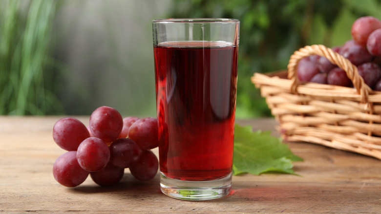 woman drinking a dark red juice with a straw