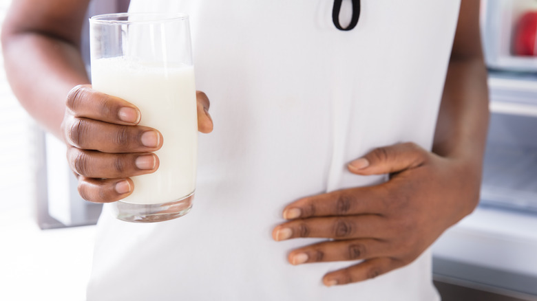 Person holding milk glass touching stomach